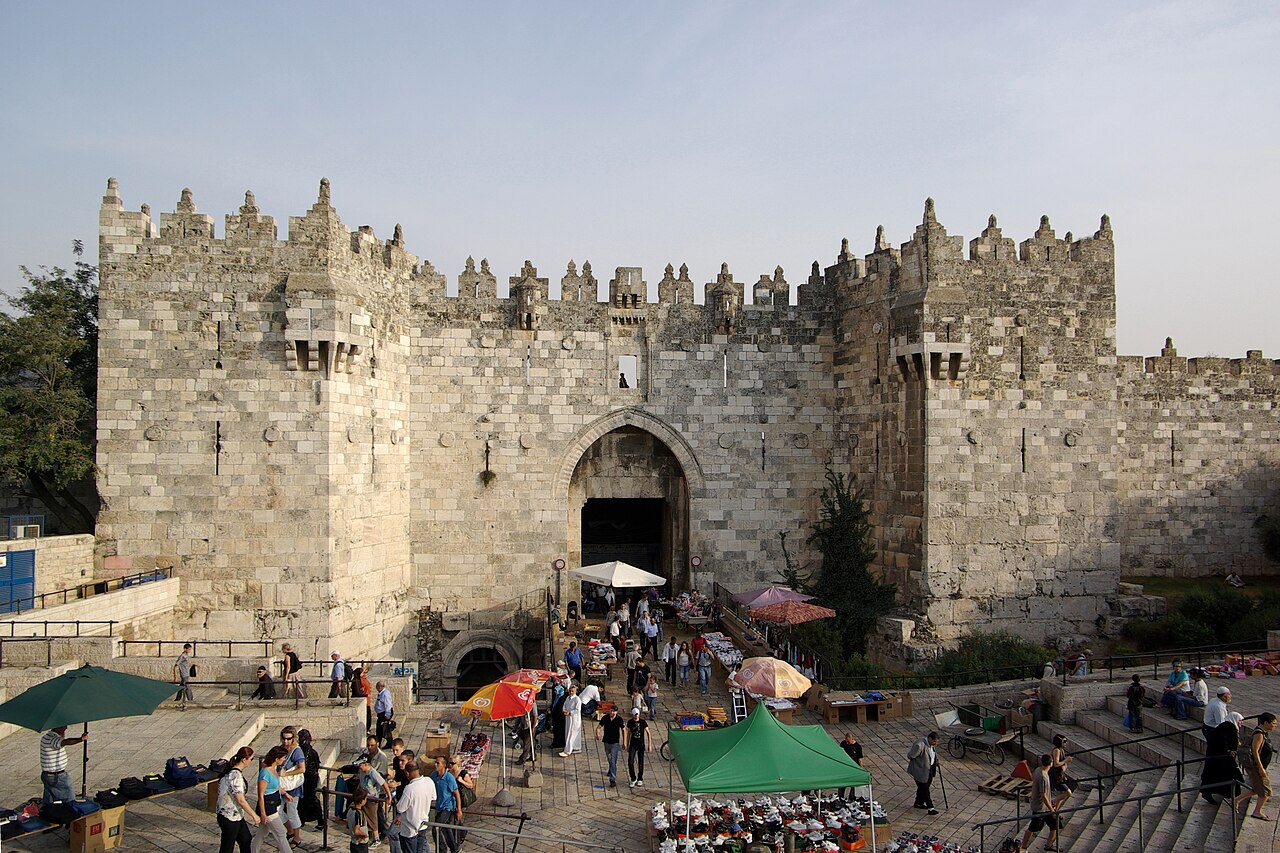 A picture of the Damascus Gate in Jerusalem showing the vendors and tourists within the gate.